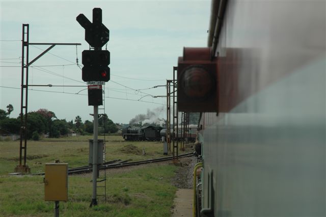 Departing Rayton on the branch to Cullinan, the 15F number 3117 makes for an interesting sight framed by the dead signal. There was a delay whilst authority numbers were given to pass this signal at danger, as the signal was temporarily out of order. The branch line to Cullinan starts at this point. In the very early days of Rayton station, there was a triangle, of which some of the earthworks can still be seen, and this section of the line was not in existence untill much later. Feb 14th Valentines day train.