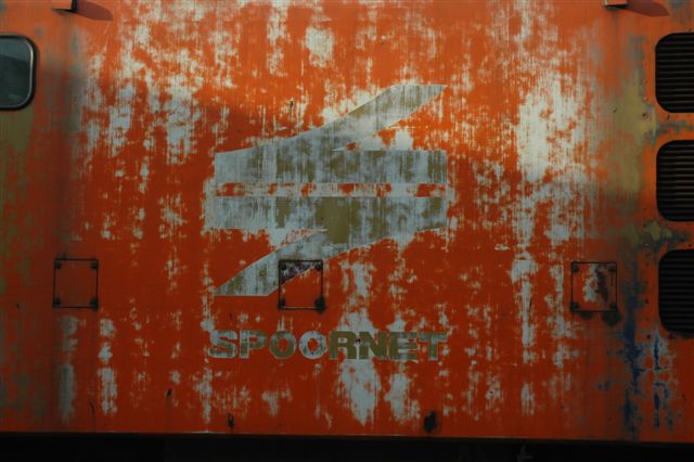 Sign of the times. A faded Spoornet emblem on the side of a class 5E1 electric now the property of Rovos Rail. The once familiar orange colour scheme was an attempt at modernising the old red and grey schemes of the old railway system. Soon this unit will proudly bear the Rovos green