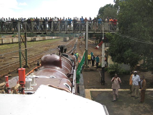 Leaving the station and passing under the crowded footbridge. Both the main signal and the shunting signal ahead are at "proceed" - NB signals inside the yard and station area are lower quadrant, unlike the upper quadrant signals out on the main line