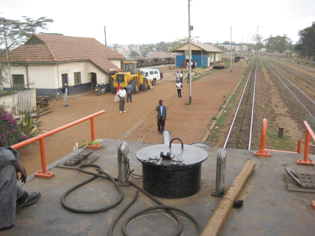 Jane (next to lamp post) waits on the platform at Athi River as the train pulls in. She came to pick me up in the Land Cruiser, which can be seen parked nearby. Photo by John