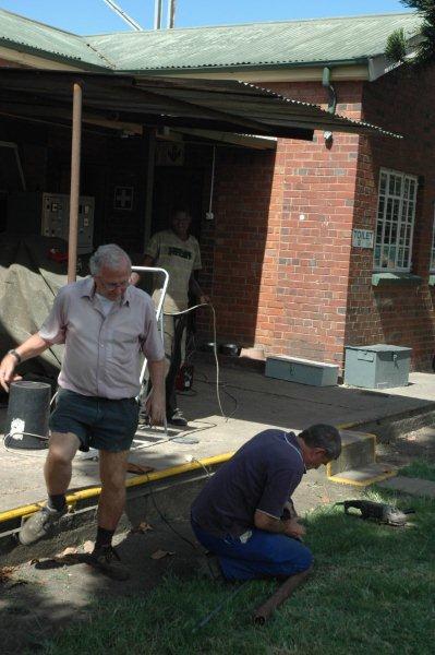 Tom about to assist Steve Smith as he finishes off a roof sheet for the newly constructed covering for the generator. Note the roof is on and soon painting will commence.