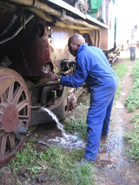 Boilermaker Wilson loosens a washout plug on 3020 as water pours out of the blowdown cock in preparation for the boiler inspection