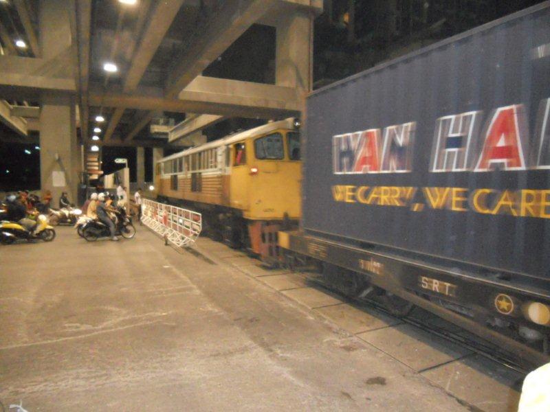 A very grab shot at night with a borrowed camera, sees the diesel hauled freight passing one of the many boom gated level crossings in the city of Bangkok