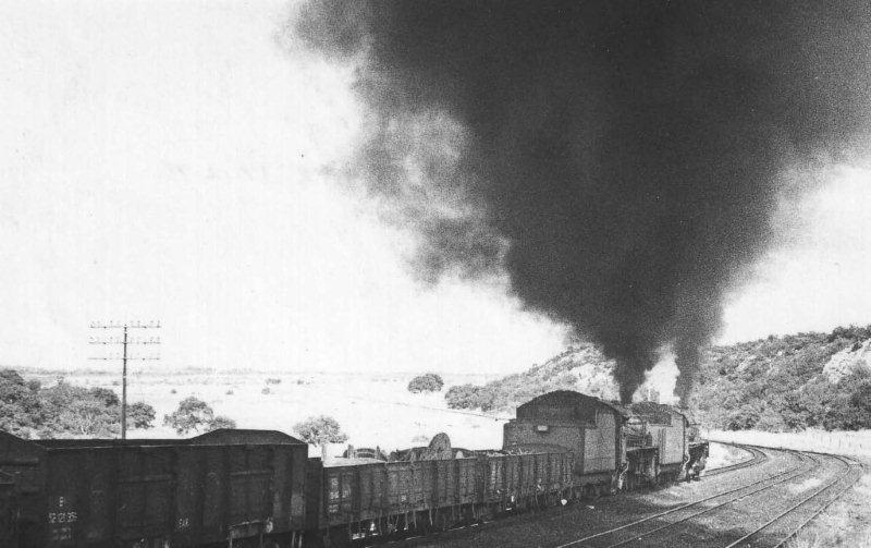 The silence of Panpoort is ripped apart as these 15CA locomotives open up for the long haul to Rayton, as they move the load of coal Eastbound. Numbers 2808 and 2055 during 17 December 1971