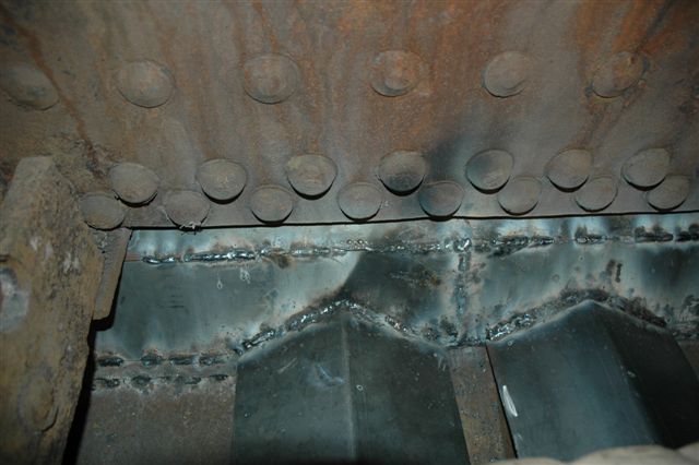 The sealing up of 15F 3117 ashpan. The view here is the cab end of the firebox looking down on to where the hand shaker pull rods are fitted. The open spaces of the ashpan have now been closed to prevent stray coals causing lineside fires, whilst the angled plates are fitted over the pull<br />rods to prevent build up of ash. The pitch in the plates will let the ash fall away.