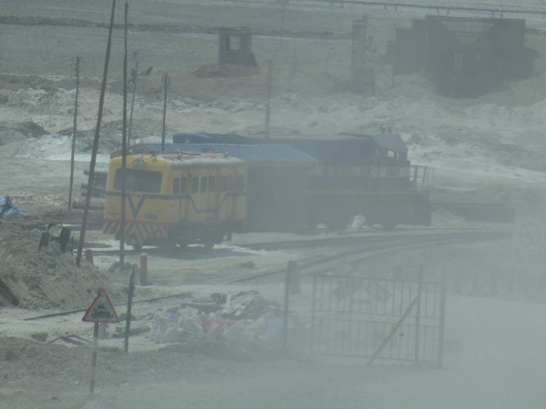 5001 and a strange yellow railcar are just visible through the dust
