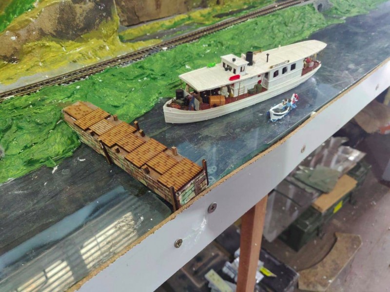 The "African Queen" comes in to land at a small stone jetty as a small boat with an outboard motor keeps pace.