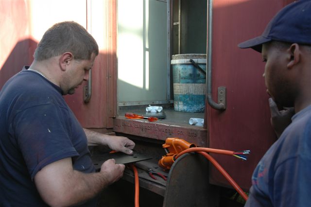 Gabor and John M do some minor adjustments to the plug point mounting plates. The coaches will now have some current day electricity.<br /><br />Photo by Nathan Berrelowitz 18/08/07