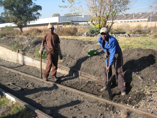 Two casual labourers continue to dig away the earth at the side of the track