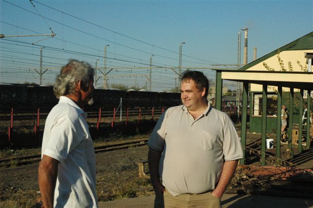 Koos gives a smiling Arno an update on the newsite progress, as they stand at the departure point, whilst just visible in the background, Tom and John A are affixing signage!