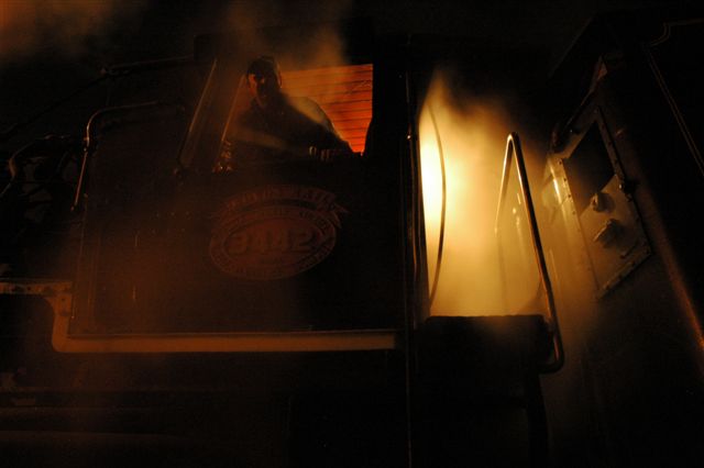 Light at night. The driver looks down from his perch as the 25NC is awaiting to clean fire at the Rovos ashpits