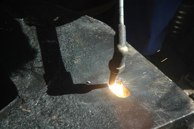 The contrast of light and dark, as the acetylene cutter enlarges a hole in the firebox door frame