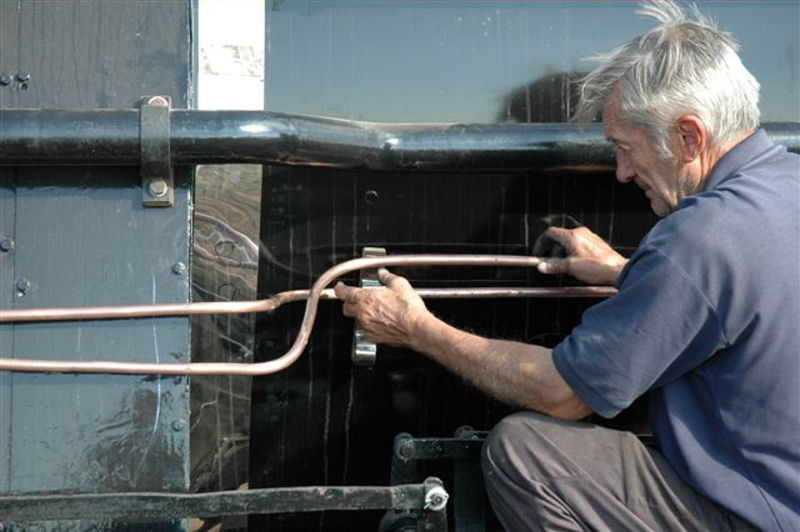 JOHN DADFORD, GETS HIS EYE IN ON SOME PIPING.<br /> WITH THE EYE AND ATTITUDE OF A TRUE PERFECTIONIST, HE JUDGES THE DECEPTIVE<br />BENDS, AS THE LUBRICATOR PIPING ON THE DRIVERS SIDE OF 15F 3117 IS FITTED.