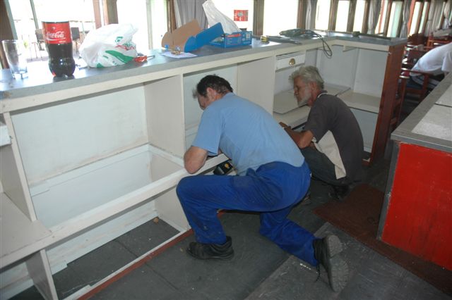 Les and Koos remove side panels and shelving to accommodate the bar refrigerator