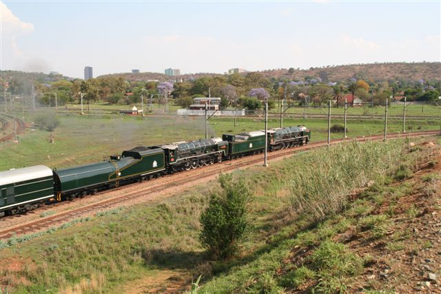 The hills of Pretoria, dotted with jacarandas in full bloom, bear witness to the departure of 3484 and 3442. An interesting comparison of the tenders is possible in this view.