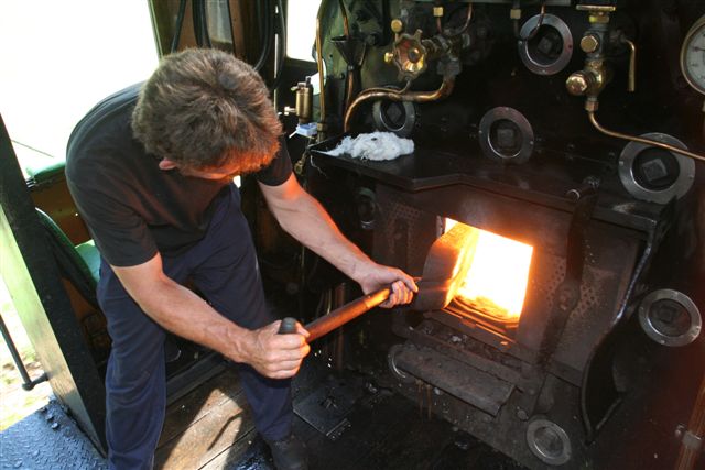 Throwing the coals - the muscled arms of fireman Arrie power the locomotive