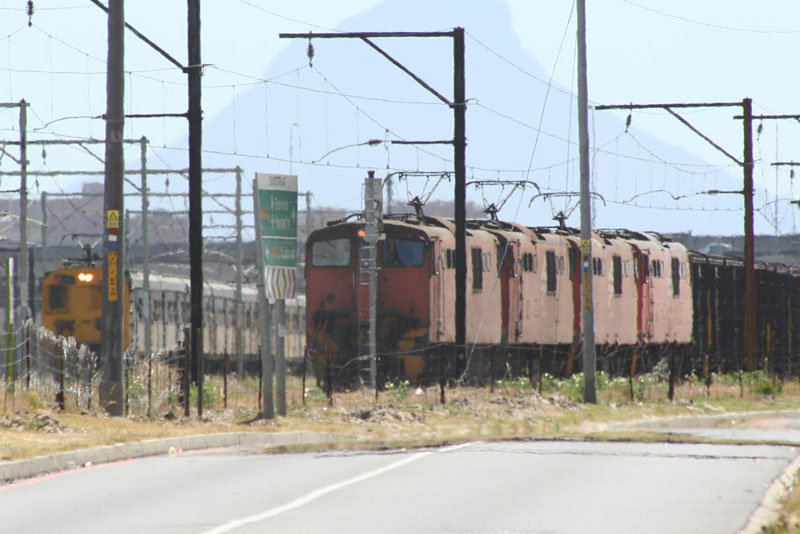 A Metro departing Bellville on its way to Kraaifontein passes the waiting Freight.